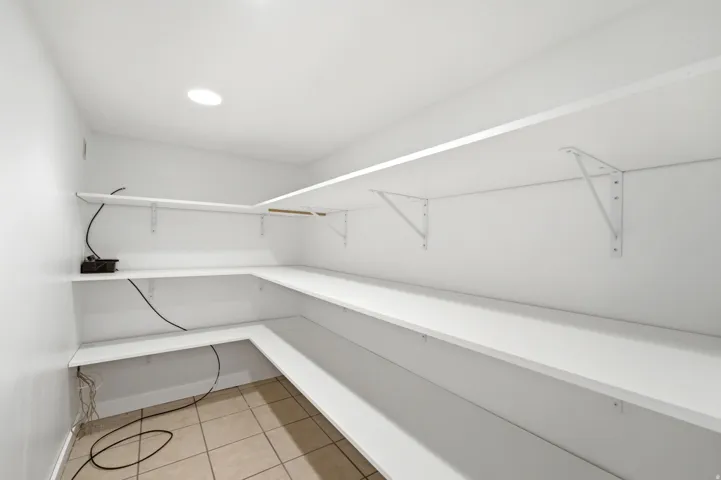 Built-in shelving with white finishes, recessed ceiling lighting, and neutral tile flooring