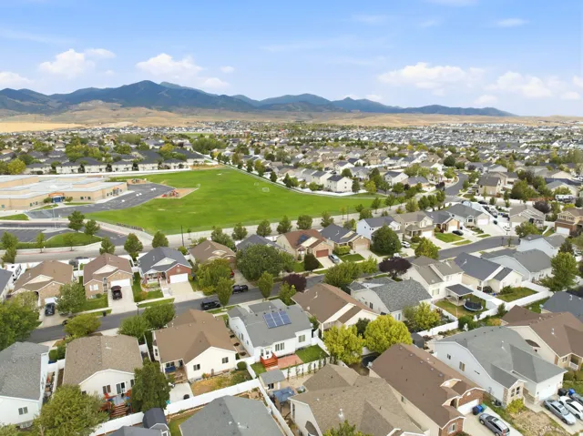Expansive residential area with a large green field and beautiful mountains in the background. An off leash dog park is close as well