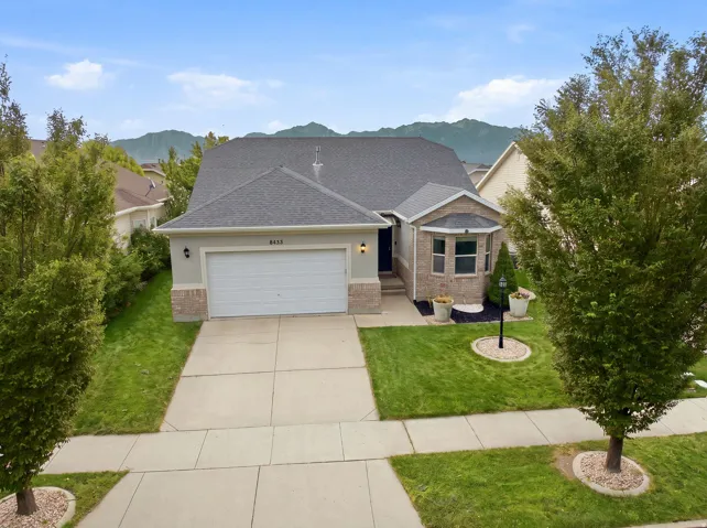 Mountain backdrop, brick and stucco exterior, bay window, attached garage, and manicured landscaping
