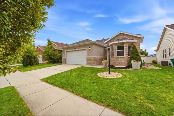 Brick and stucco exterior, attached two-car garage, bay window, concrete driveway, and front lawn