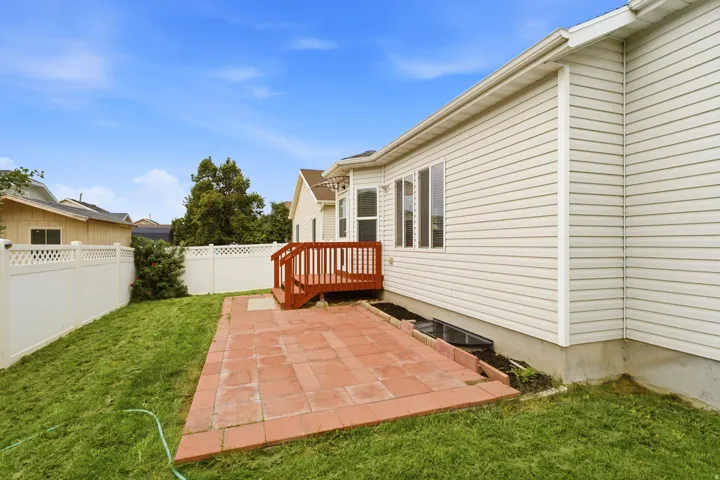 Redwood deck, paver patio, vinyl siding, white privacy fence, and multiple windows