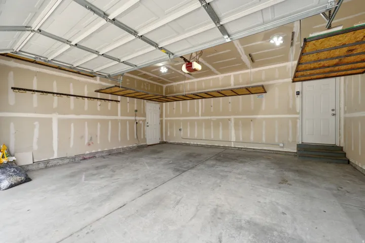 Spacious garage featuring a concrete floor, overhead garage door, and built-in overhead storage shelves