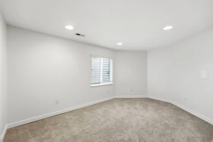 Recessed ceiling lighting, carpet flooring, window with blinds, and white painted walls