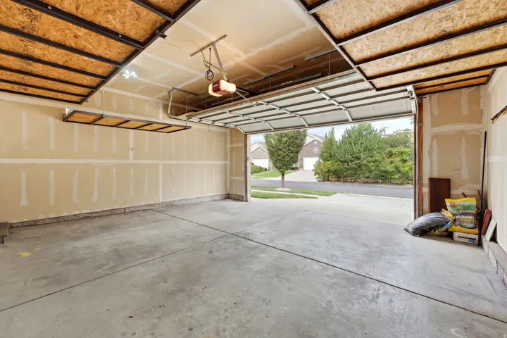 Garage with concrete flooring, overhead storage racks, garage door opener, and overhead lighting
