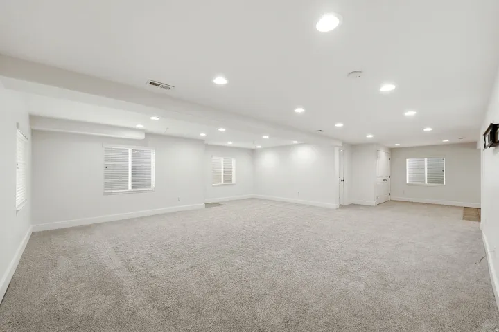 Expansive rec room with neutral carpet flooring and recessed lighting, wired for a theatre room as well
