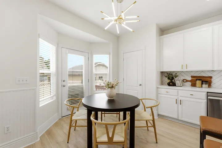 Bay window dining area with wood-finish flooring, white wainscoting, and a modern linear chandelier