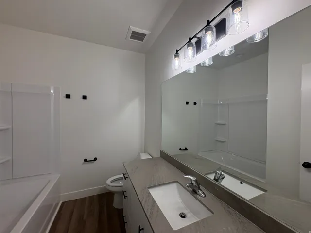 White vanity with a single basin sink, matte gray countertop, and chrome faucet