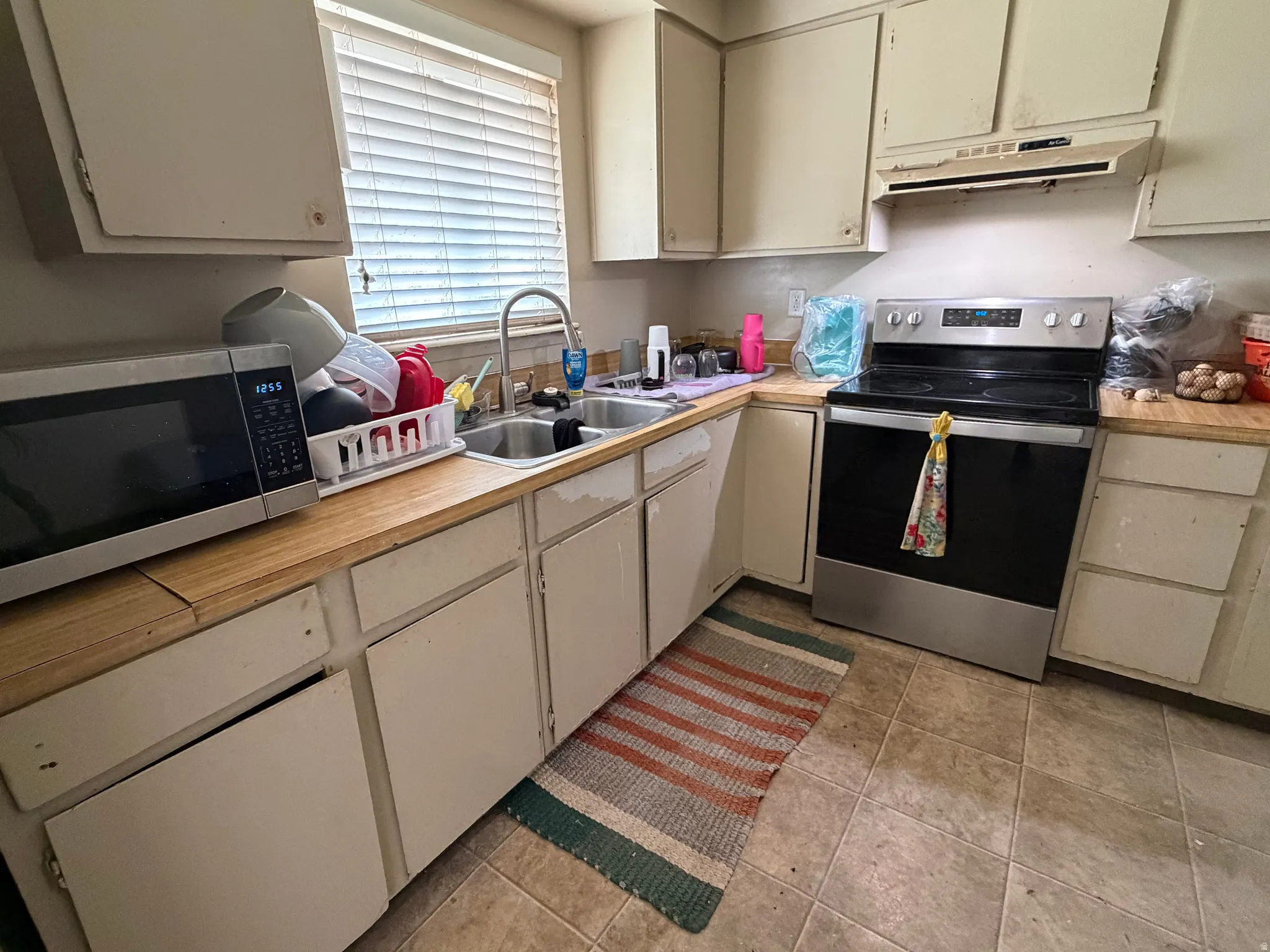 Kitchen featuring a dual basin sink with a high-arch faucet, a stainless steel electric range, and wood-finish countertops
