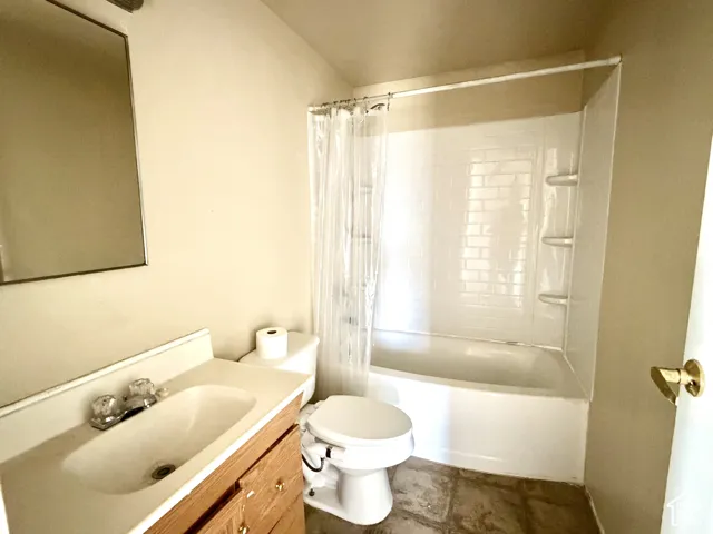 Recessed medicine cabinet, wood-finish vanity with integrated sink, toilet, and a shower-over-tub combination with subway tile surround