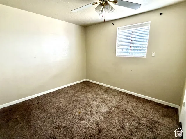 Carpeted room with a window, white trim, and a ceiling fan with integrated lighting