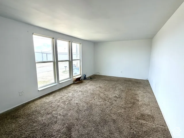 White painted walls and broadloom carpeting with multiple window panels