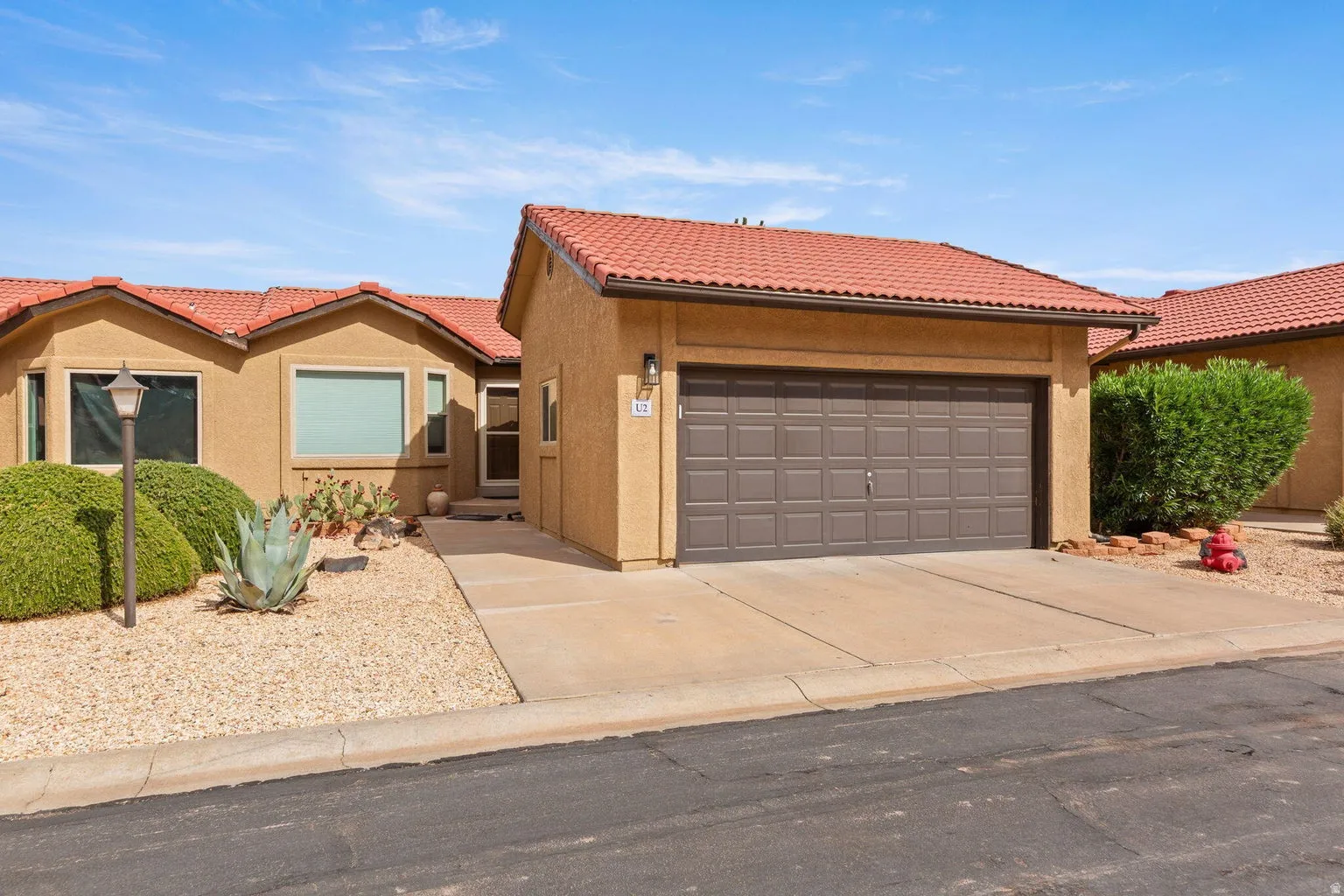 Stucco exterior with terracotta-style roof tiles, an attached garage, and a concrete driveway