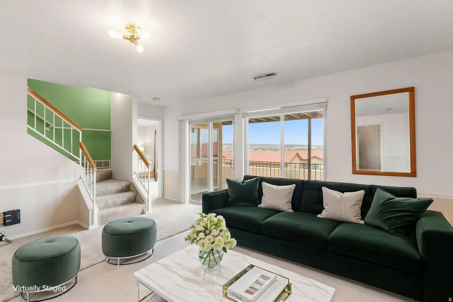 Sliding glass doors, staircase with wood handrail, ceiling-mounted light fixture, white walls, and carpeted flooring