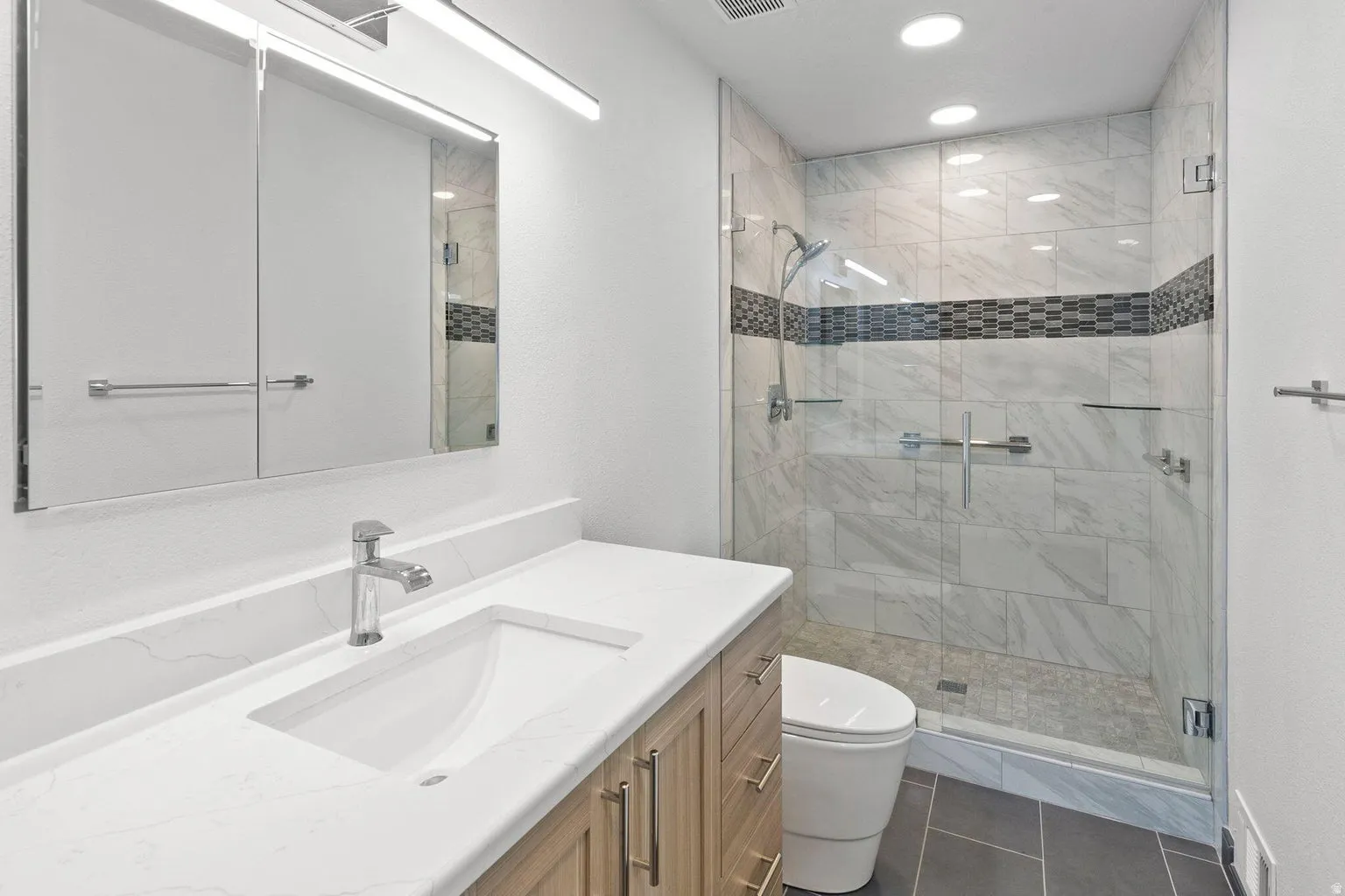 Vanity with integrated sink, chrome faucet, and mirrored medicine cabinet