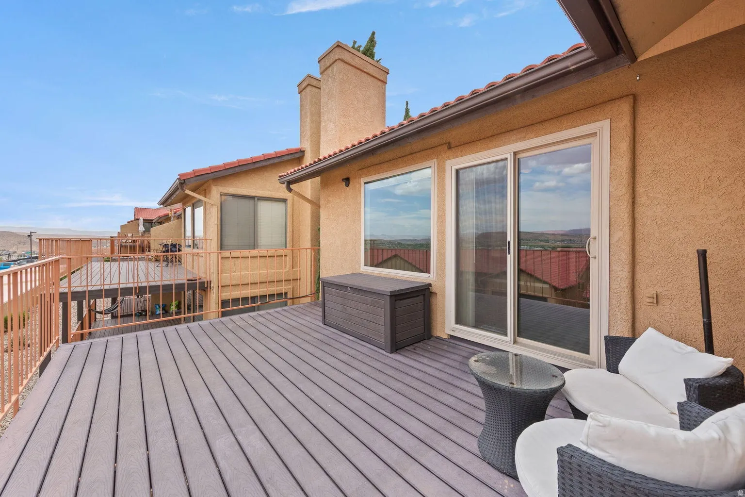 Expansive deck with composite decking, metal railings, stucco exterior, and sliding glass doors