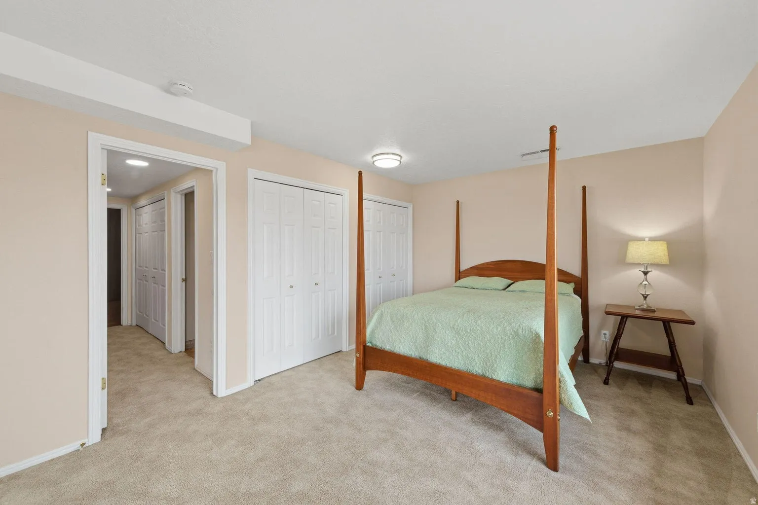 Carpeted flooring, neutral wall tones, two white bi-fold closet doors, and recessed lighting