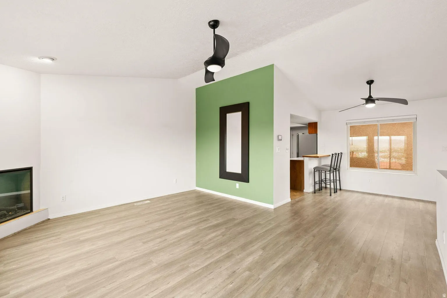 Vaulted ceilings, wood-finish flooring, a built-in fireplace, and modern ceiling fans