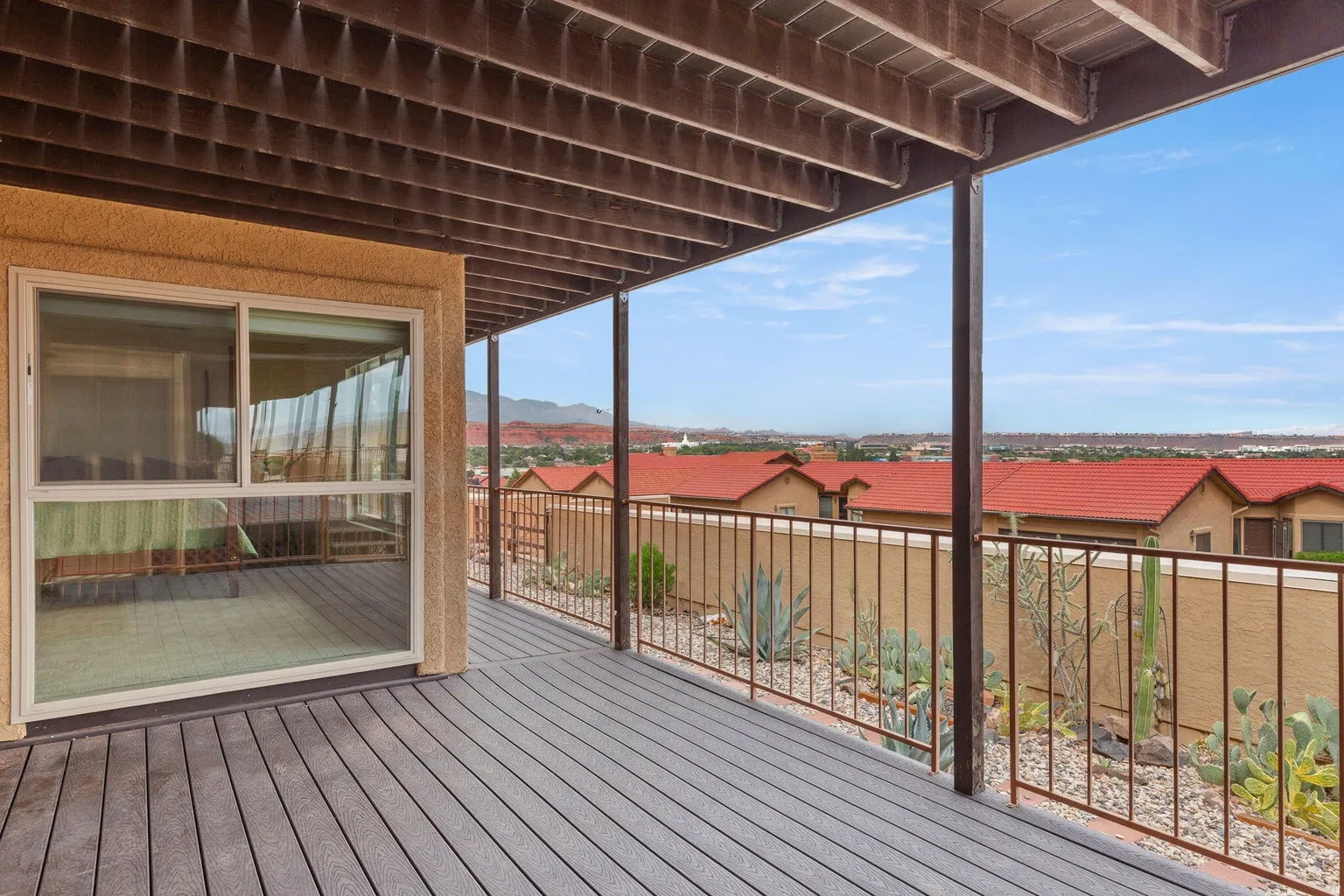 Expansive covered deck featuring composite decking, protective railing, and a desert-style landscape