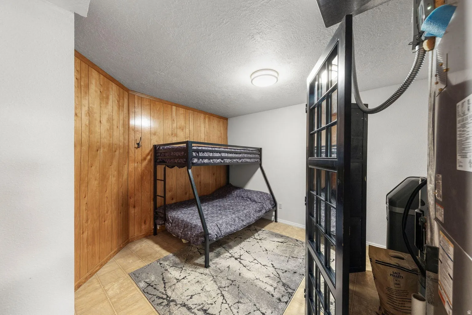 Wood paneling accent wall, light-colored tile flooring, flush mount ceiling light, and white painted walls