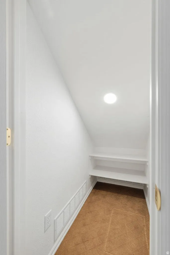 Recessed ceiling light, built-in shelving, wall-to-wall carpeting, and sloped ceiling
