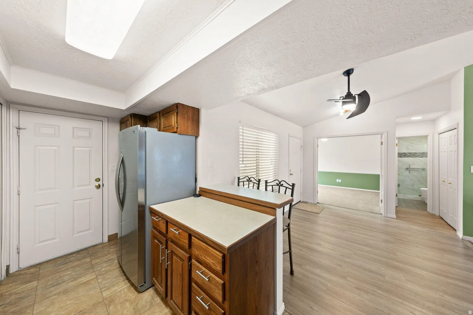 Kitchen featuring wood cabinetry, stainless steel refrigerator, and tiled flooring