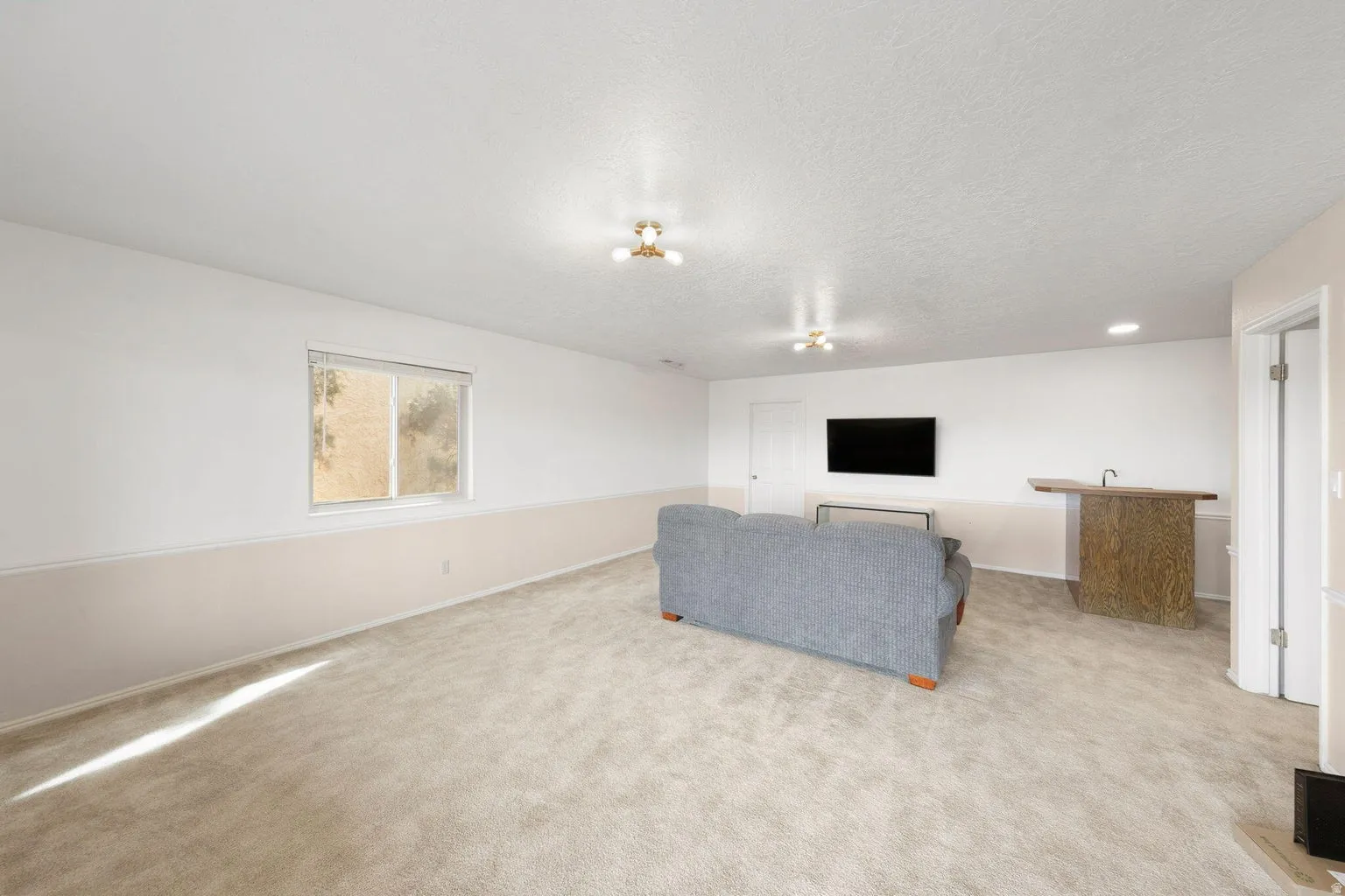Carpeted room featuring a window, built-in bar with sink, and recessed lighting