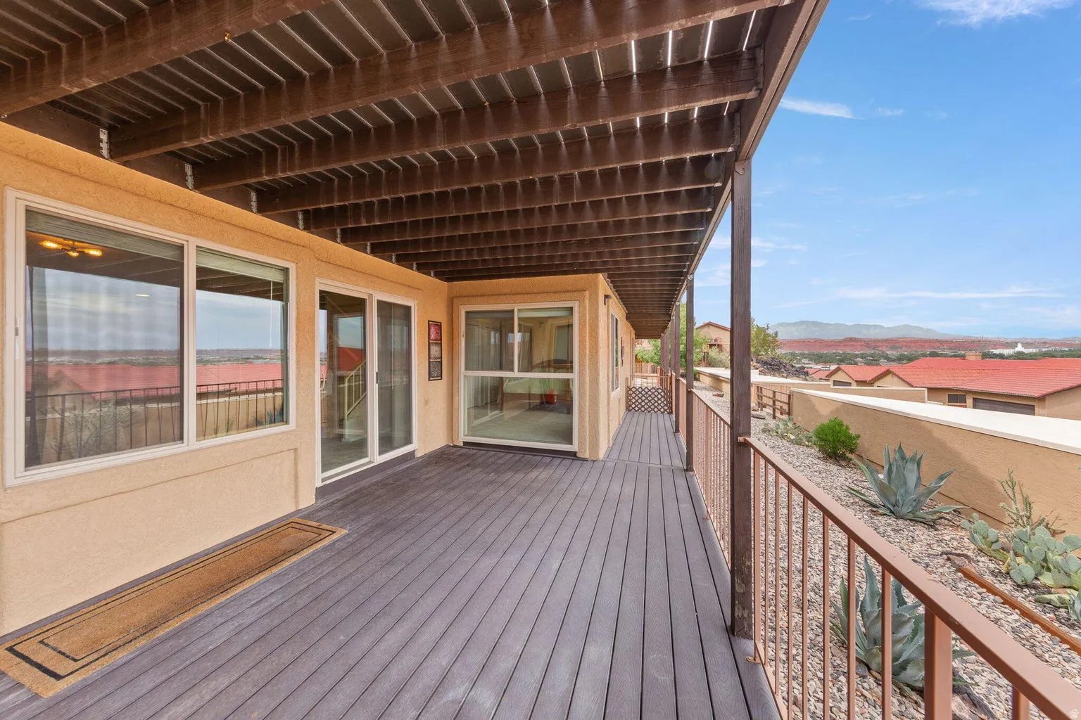 Expansive covered deck featuring a dark composite surface and metal railing