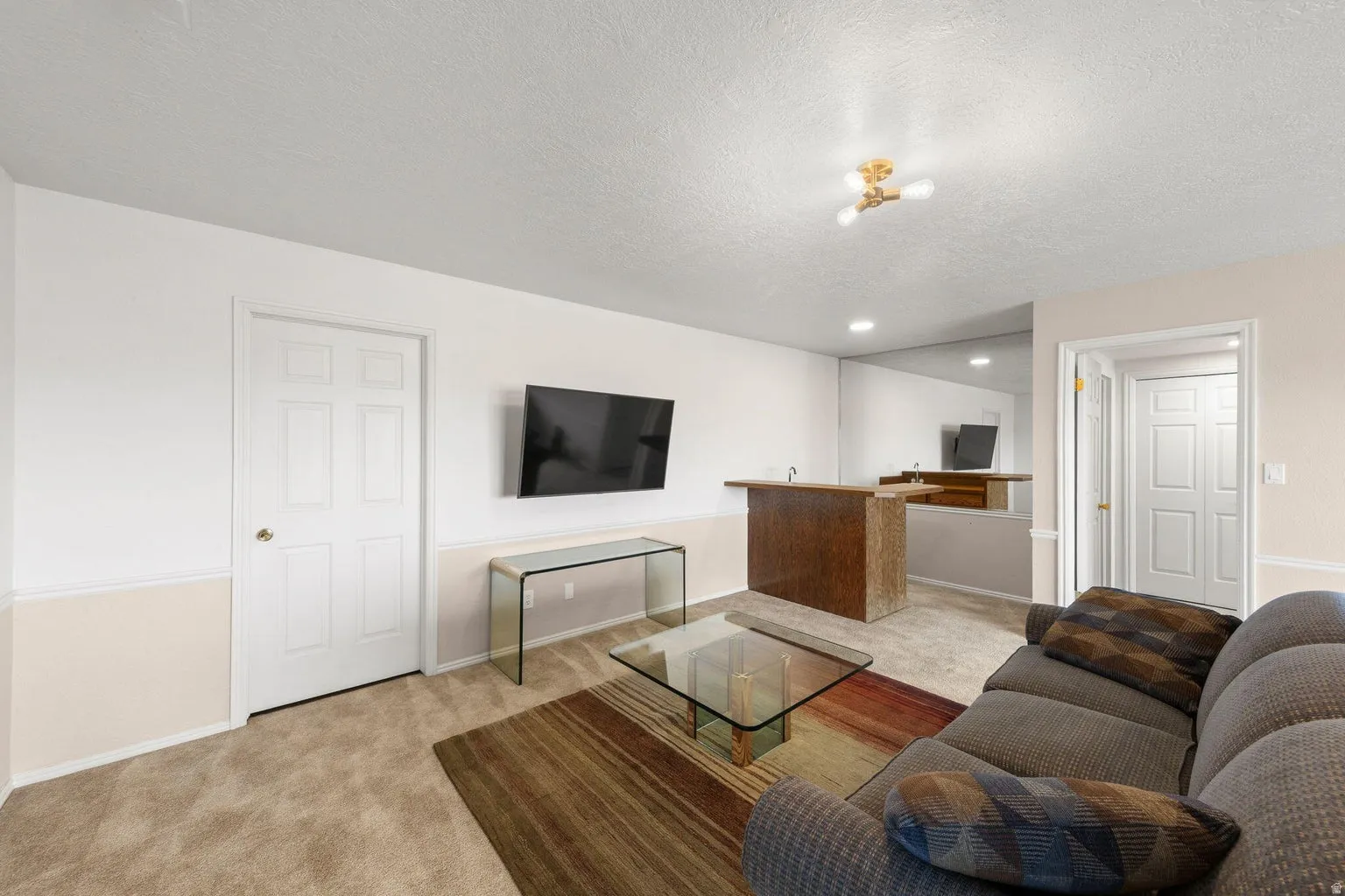 Carpeted flooring throughout, recessed lighting, and a built-in wet bar with a basin sink