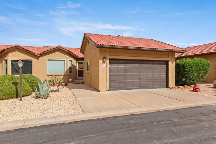 Stucco exterior with terracotta-style roof tiles, an attached garage, and a concrete driveway
