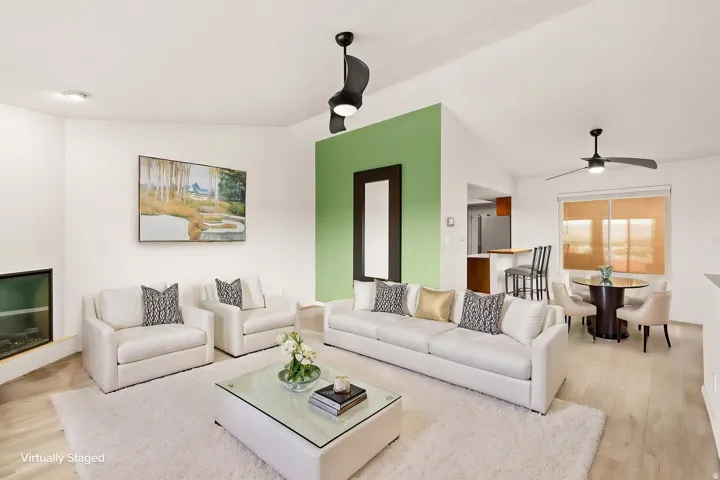 Open-concept living space featuring vaulted ceilings, a built-in fireplace, wood-finish flooring, and recessed lighting