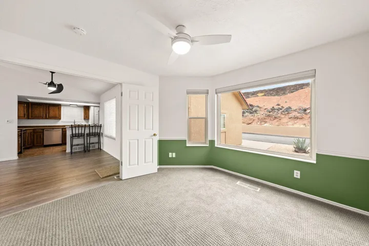 Carpeted living space with a ceiling fan, a large bay window, and a secondary window