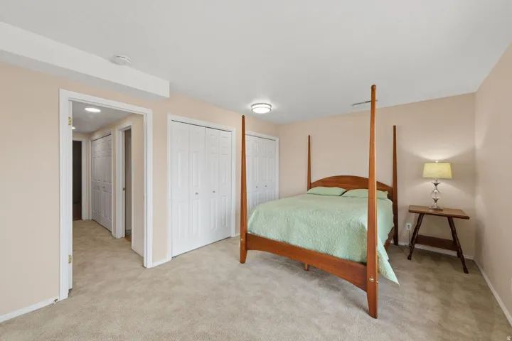 Carpeted flooring, neutral wall tones, two white bi-fold closet doors, and recessed lighting