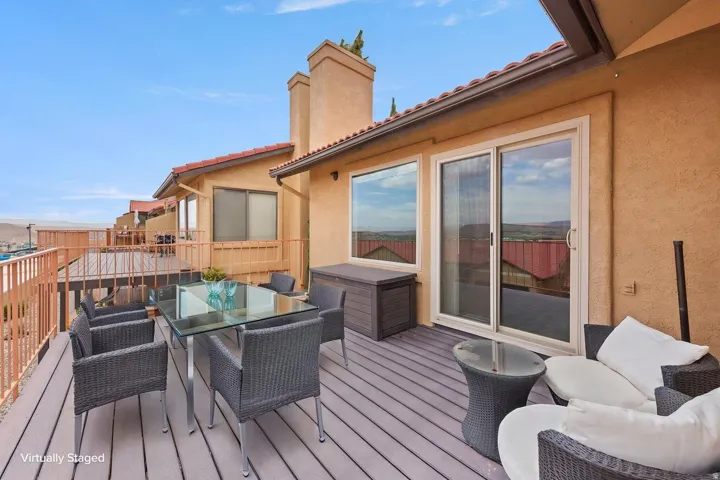 Expansive composite decking with aluminum railings, stucco exterior, and sliding glass door access