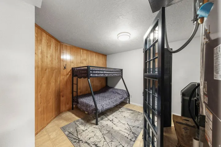 Wood paneling accent wall, light-colored tile flooring, flush mount ceiling light, and white painted walls