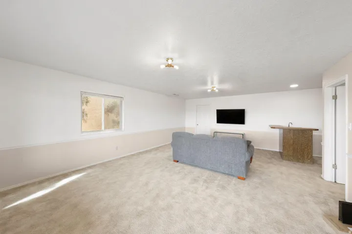 Carpeted room featuring a window, built-in bar with sink, and recessed lighting