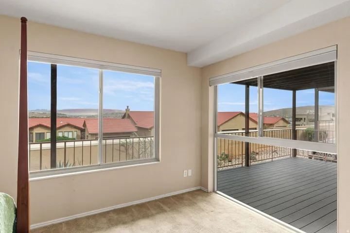 Sliding glass door opening to an outdoor deck, large window with expansive territorial scenery, and light-toned walls