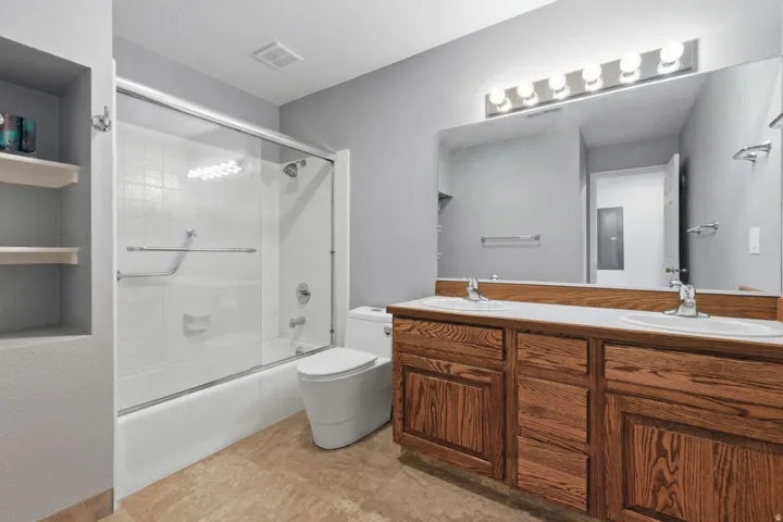 Double vanity with wood-finish cabinetry, white countertop, and dual undermount sinks