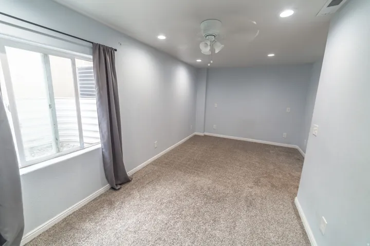 Recessed lighting, ceiling fan, and light-colored carpeting