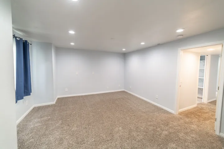 Recessed lighting illuminates this carpeted room with light-colored walls and white trim