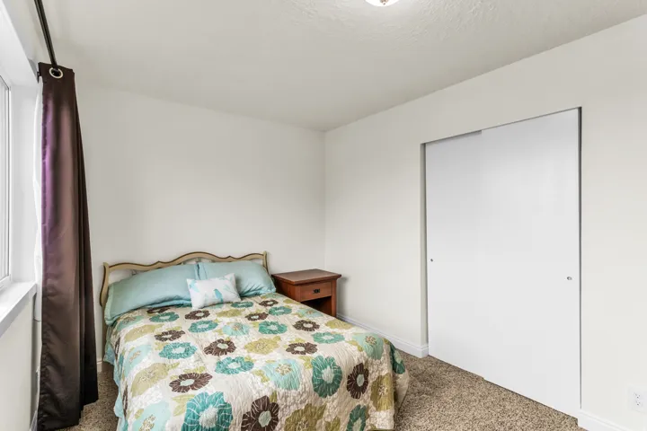 Soft carpet flooring, white walls, built-in sliding closet doors, and window with dark drapery
