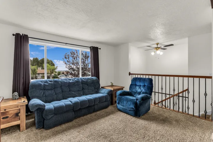 Expansive window with dark curtain panels, carpeted flooring, white walls, and a ceiling fan