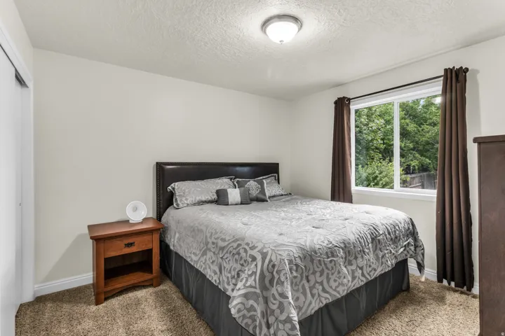 Textured ceiling, wall-mounted light fixture, white window trim, brown carpet, and white baseboards
