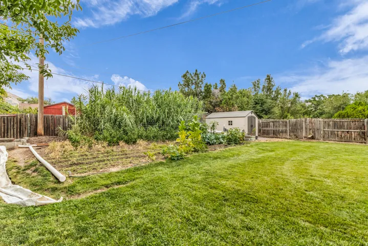 Expansive backyard featuring a manicured lawn, established garden beds, and a wood privacy fence