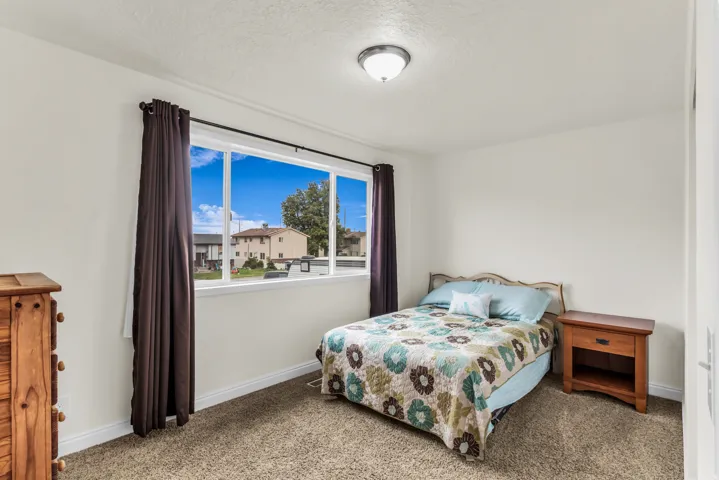 Spacious room featuring a large window, neutral wall tones, and plush carpeting