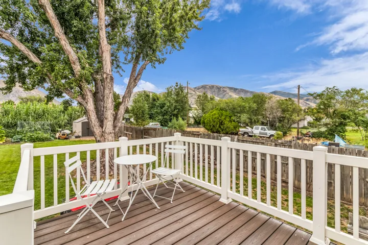 Trex deck with white railings and mature trees full fenced back yard