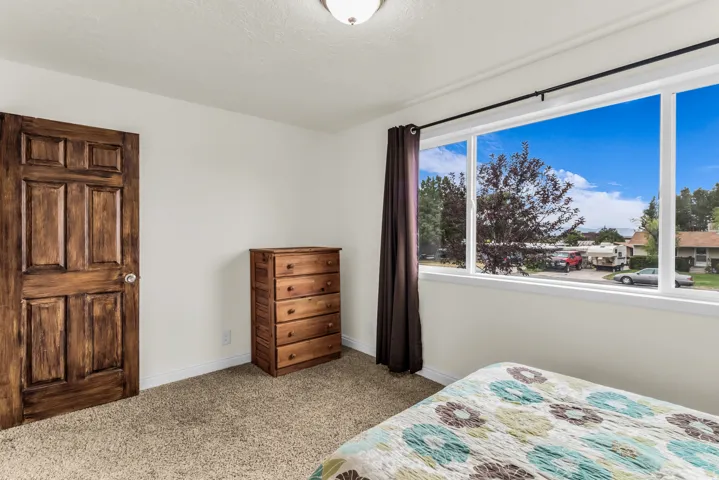 Expansive window with white framing, plush carpet flooring, white painted walls, and a recessed ceiling light