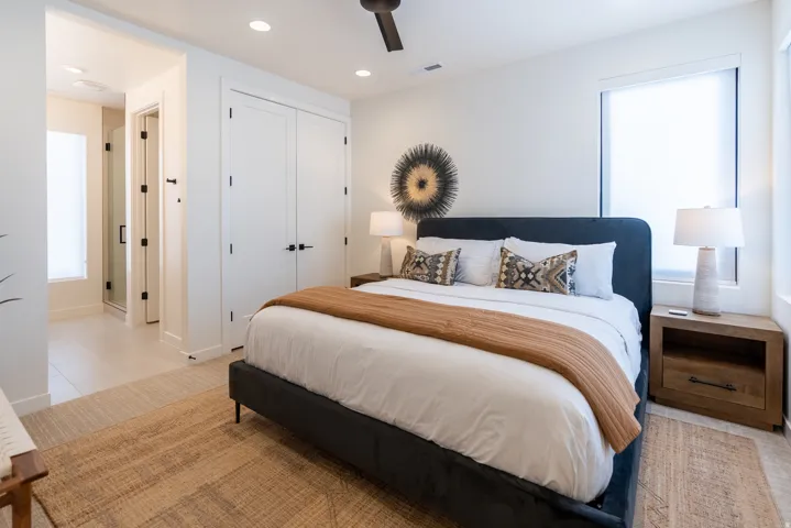 Recessed lighting, ceiling fan, double-door closet, large window with roller shade, and tiled flooring extending into the bathroom