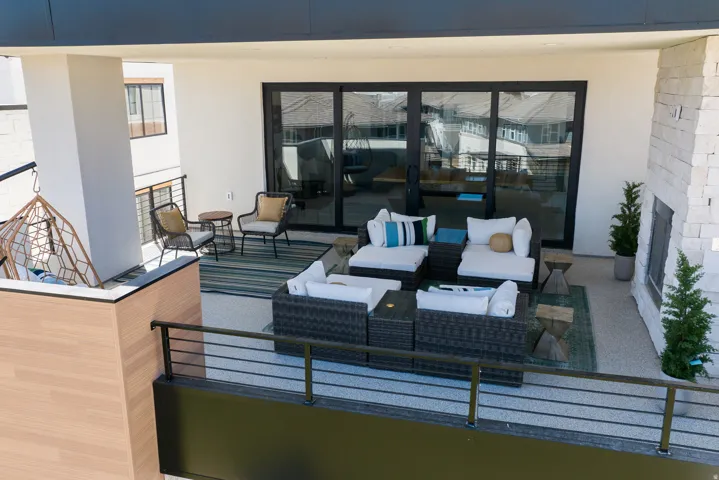 Spacious outdoor patio with sliding glass doors, stone fireplace, and metal railings