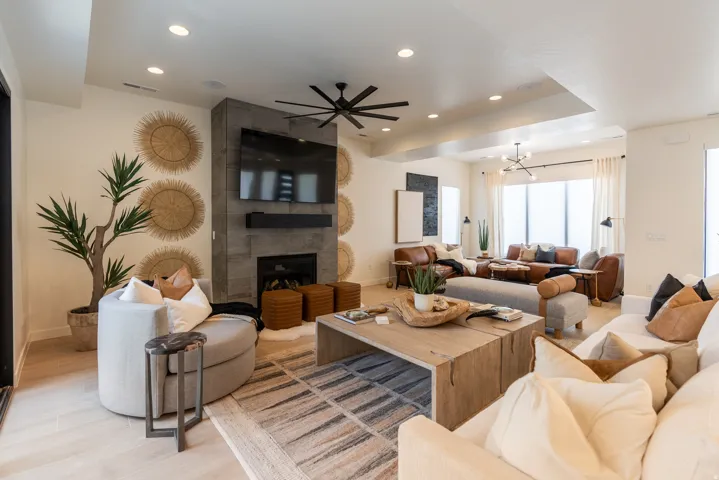 Spacious living area featuring a stone-clad fireplace, wood-finish flooring, recessed lighting, and a contemporary ceiling fan