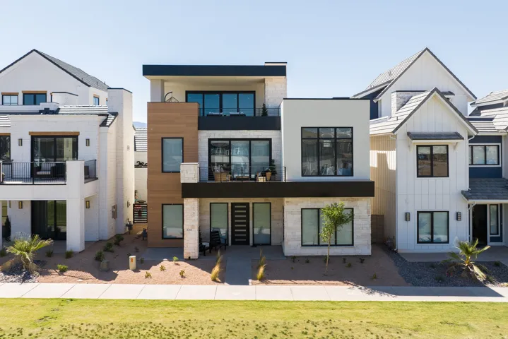 Contemporary exterior with wood-finish siding, stone accents, black-framed windows, a flat roofline, and multiple balconies